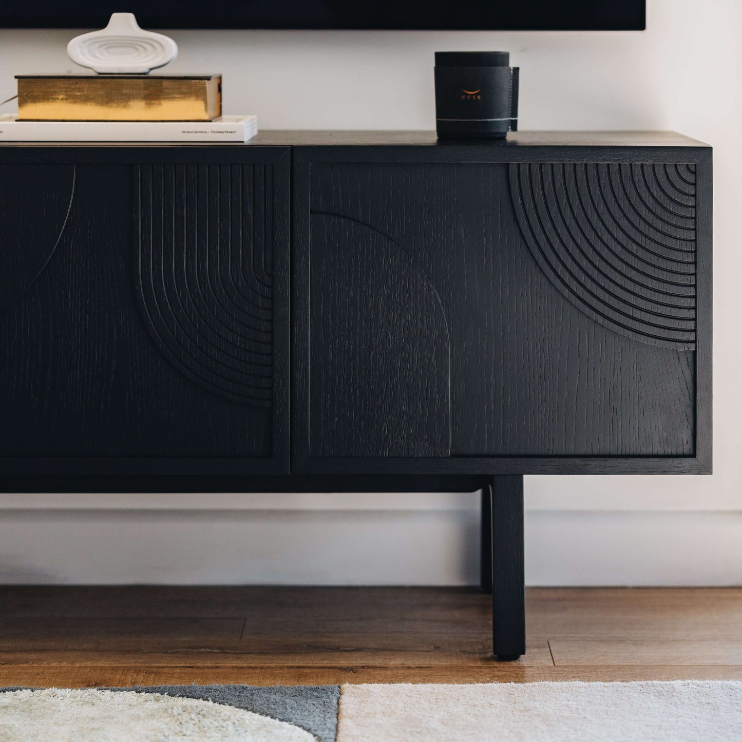 Modern black sideboard with stylish geometric patterns standing on wooden floor, accented with decorative items, minimalist decor