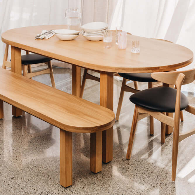 Modern wooden dining table set with chairs and bench, featuring minimalist design and black seat cushions.