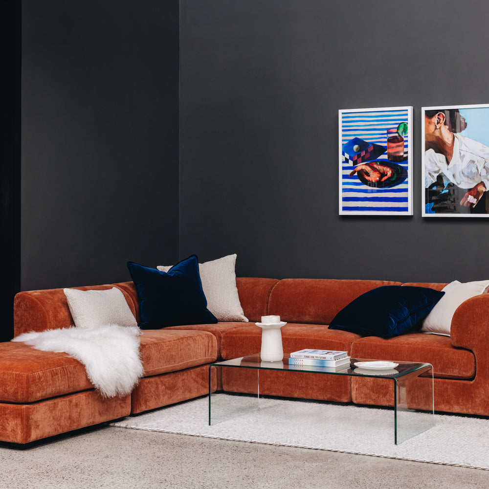 
                      
                        Modern living room with an orange sectional sofa, coffee table, and wall art.
                      
                    