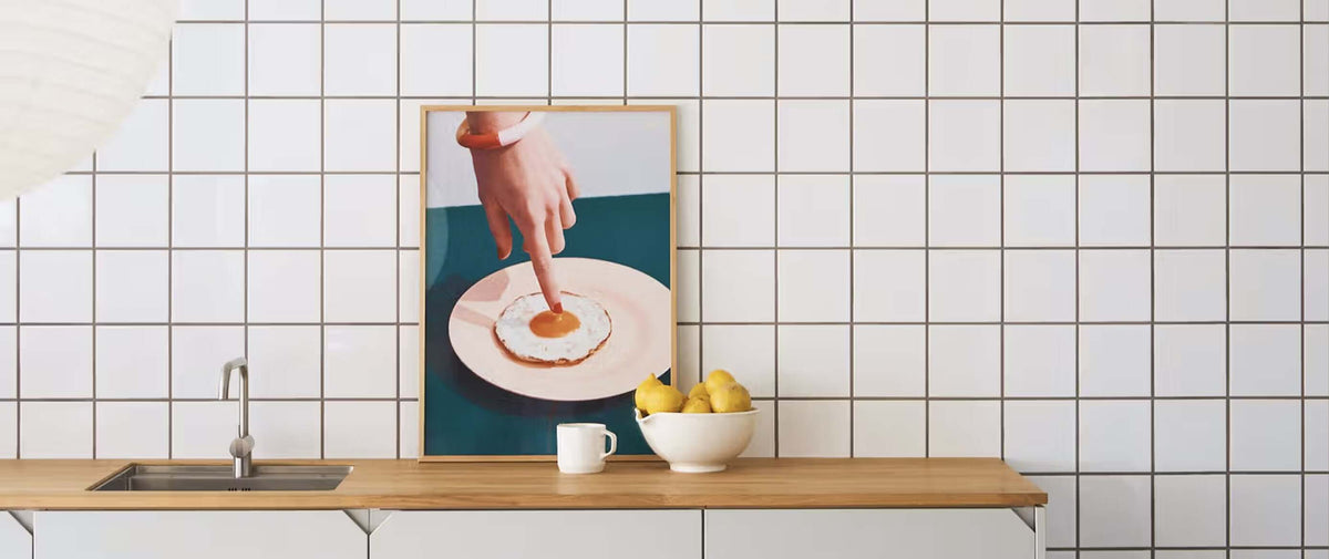 Modern kitchen countertop with decorative art, lemons, and a white tiled backsplash.