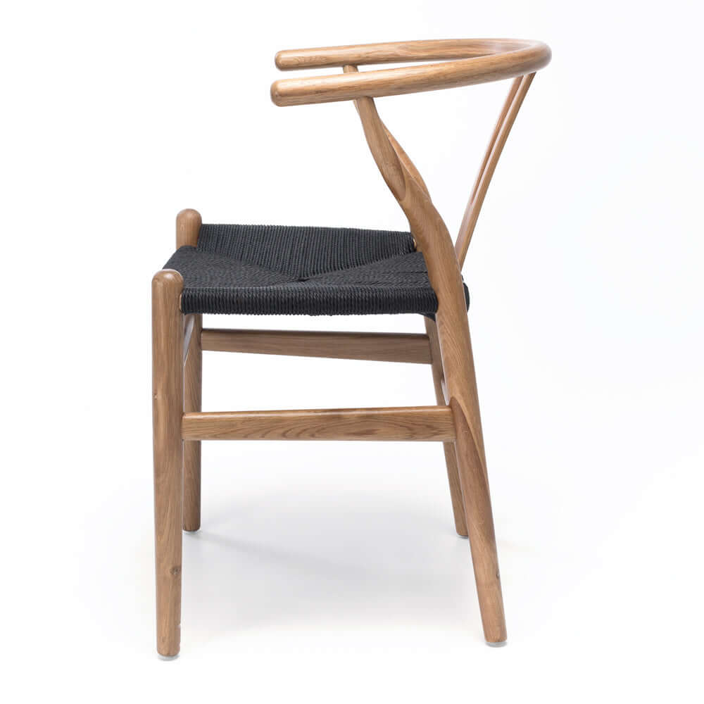
                      
                        Side view of replica Hans Wegner Wishbone Dining Chair with oak wood grain and black rope seat, mid-century style.
                      
                    