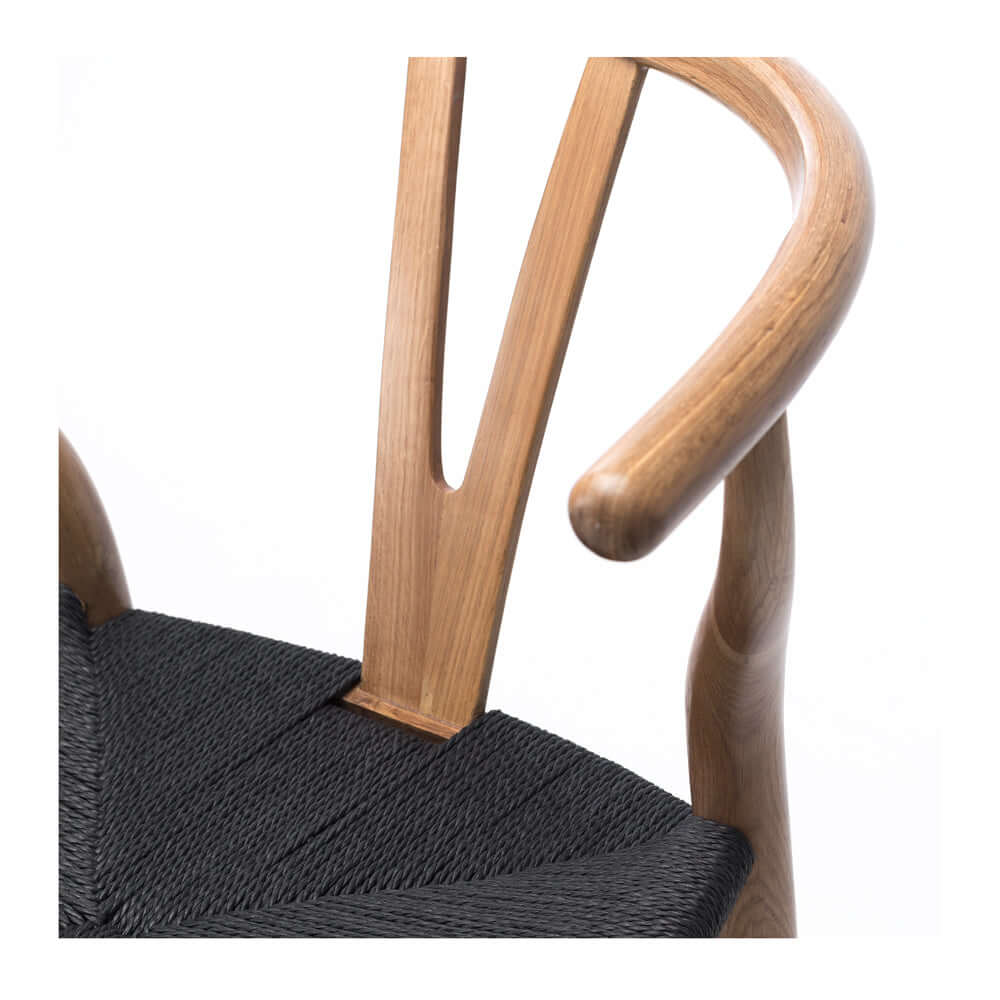 
                      
                        Close-up of Wishbone Dining Chair with natural oak woodgrain and black rope seating, highlighting steam-bent back and arm rail design.
                      
                    
