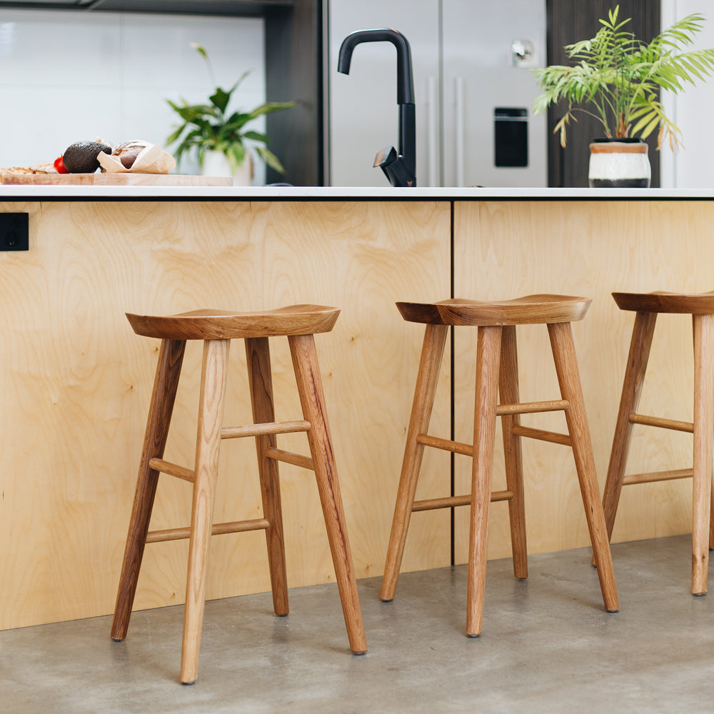 
                      
                        Fuji bar stools with natural woodgrain and retro design around a modern kitchen island.
                      
                    