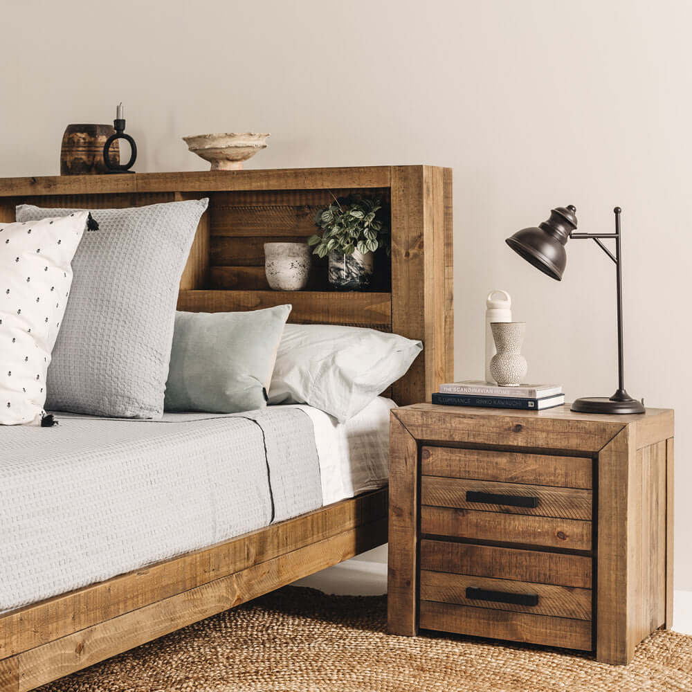 Rustic wooden bed set with a cozy gray blanket and pillows, accompanied by a matching nightstand and a modern desk lamp.